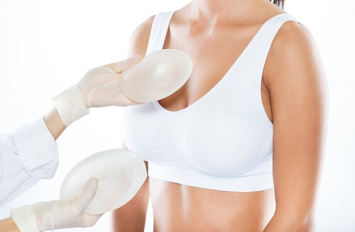 Female doctor choosing mammary prosthesis with her patient over white background. Portrait of female doctor choosing mammary prosthesis with her patient over white background.